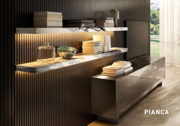 Mueble de salón moderno con estanterías flotantes de mármol iluminadas, panel de pared con listones verticales oscuros y aparador bajo con libros y objetos decorativos junto a ventanal con luz natural