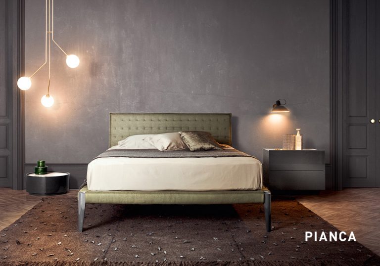 Dormitorio elegante con cama tapizada en tono verde, pared gris texturizada, iluminación colgante moderna y mesillas minimalistas sobre suelo de madera con alfombra oscura