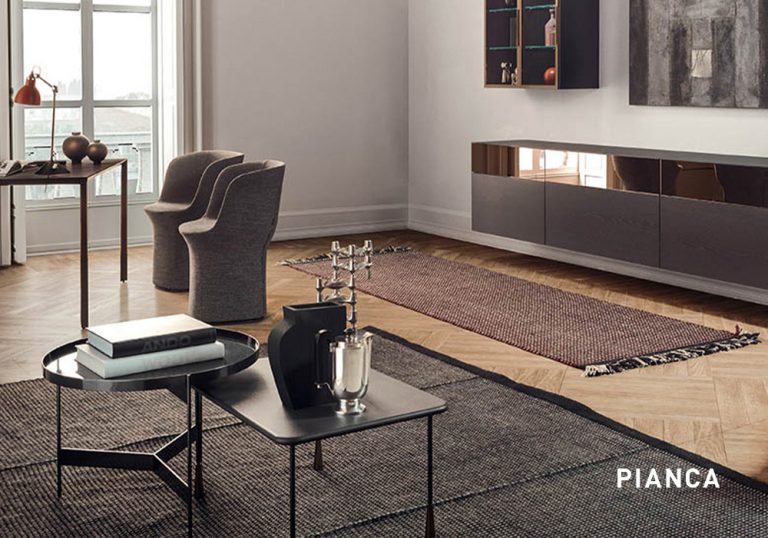 Salón moderno con muebles minimalistas, mesa de centro metálica, alfombra texturizada, sillas tapizadas junto a ventana y aparador suspendido en pared clara con decoración contemporánea